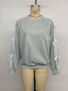 Detail of grey sweatshirt showing white lace inserts and satin bow accents on sleeves