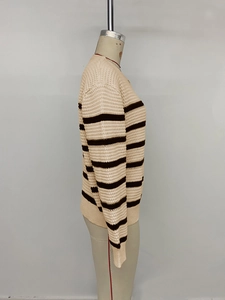 Detail of loose beige and brown striped knit sweater showing ribbed cuffs and texture