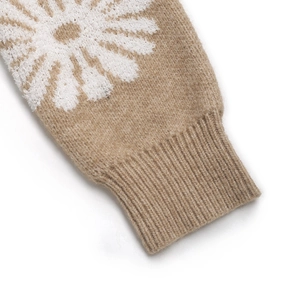 Nahaufnahme der Rippbündchen an einem camel-farbenen Strickpullover mit weißen Gänseblümchen