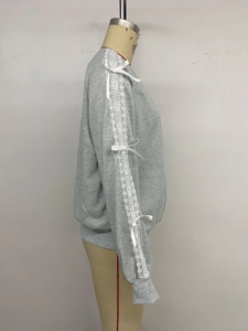 Detail view of grey sweatshirt sleeves with white lace patchwork and decorative ribbon bows