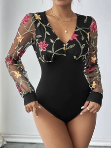 Détail des manches en résille noire et de la broderie florale complexe sur le body
