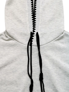 Dettaglio del ricamo nero sulla felpa oversize grigio chiaro con coulisse regolabile