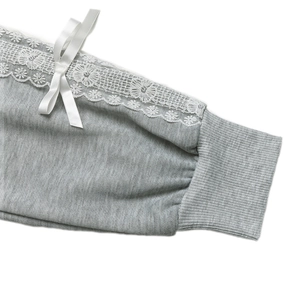 Detailed view of gray sweatshirt cuffs with white floral lace and ribbon bow
