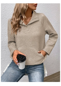 Detail eines beigen strukturierten Langarm-Sweatshirts mit 3-Knopf-Kragen und Vordertasche