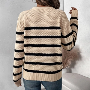 Women's beige striped waffle knit sweater styled with blue jeans in a cozy setting