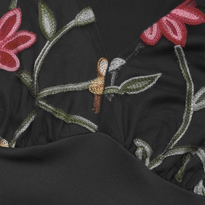 Vue détaillée des broderies florales et de la texture en résille sur le body noir à col V