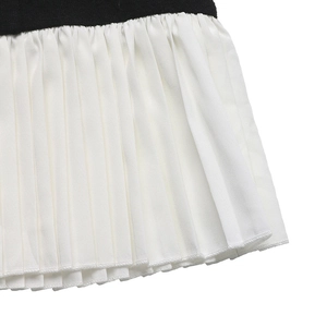 Detailed close-up showing the contrast stitch between black knit and white pleated hem