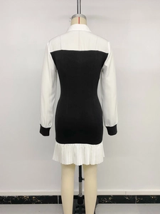 Rear view of a black long-sleeved dress with white pleated hem and elegant collar details