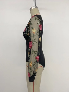 Détail d'un body à manches longues en tulle transparent avec broderies florales
