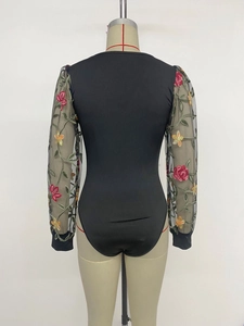 Détail des manches en tulle transparent avec broderies florales sur un body noir