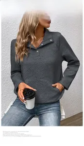 Detail eines grauen gesteppten Sweatshirts mit Stehkragen, Silberknöpfen und Tasche