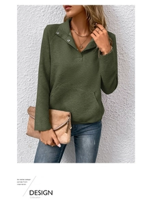 Detail eines dunkelgrünen Stepp-Sweatshirts mit Stehkragenknöpfen und Kängurutasche