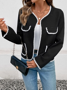 Détail de veste noire texturée avec bordure en dentelle blanche et poches élégantes