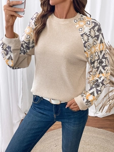Detail of waffle knit fabric and geometric ethnic print sleeves on a long-sleeve top