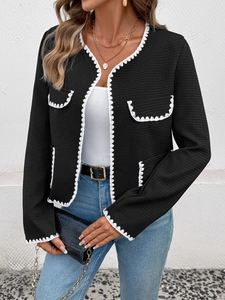 Détail de la veste cardigan noire texturée avec bordure tressée blanche et poches