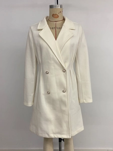 Detail of white wool coat featuring pearl buttons and tailored waist on a mannequin