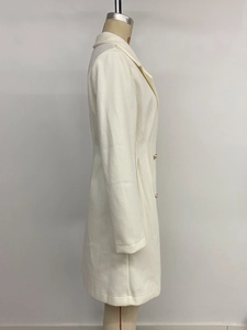 Detail view of cream-colored wool coat with elegant gold decorative buttons