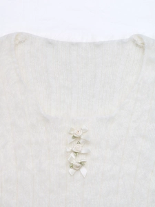 Detail of square neckline with ribbon bows and fabric roses on white fuzzy sweater