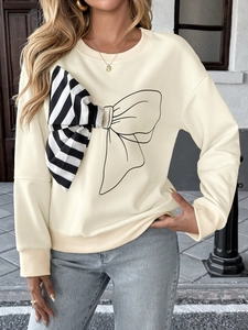Detail view of cream long sleeve sweatshirt featuring a large striped bow design and ribbed cuffs