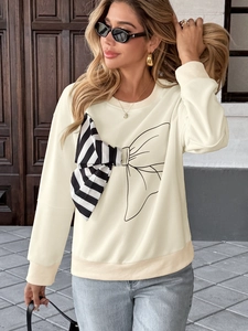 Detailed view of cream sweatshirt featuring large striped 3D bow and ribbed cuffs