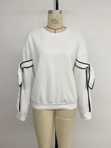 Close-up of white sweatshirt sleeve featuring black piped slits and decorative bow knots