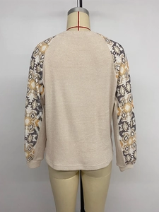 Detail of waffle knit fabric and ethnic geometric print on long sleeves of beige top