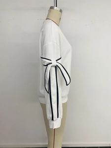 Detail of oversized bow with black piping on white long sleeve sweatshirt sleeve