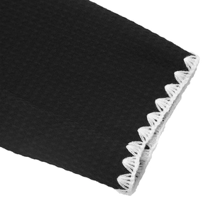 Détail macro du tissu gaufré noir avec bordure festonnée brodée blanche