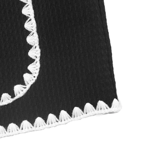 Gros plan sur un tissu noir texturé avec d'élégants détails de bordure au crochet blanc