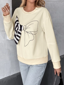 Close-up of cream sweatshirt with large graphic bow and 3D striped ribbon detail