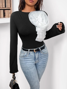 Detail of 3D white organza flower on black ribbed long sleeve slim fit bodysuit