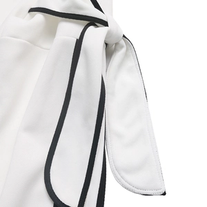 Close-up of contrast black binding and decorative waist tie on a white sweatshirt