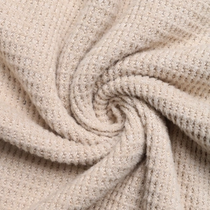 Close-up of beige waffle knit fabric texture showing soft and thick material detail