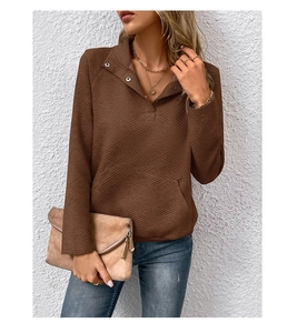 Detail eines braunen strukturierten Sweatshirts mit Silberknöpfen und Kängurutasche