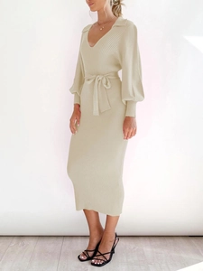 Detail of the V-neck lapel collar and lantern sleeve cuffs on a beige knitted midi dress