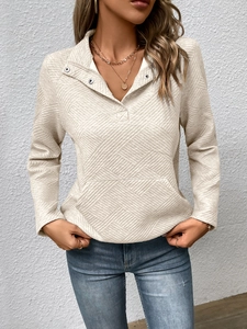 Detailansicht eines cremefarbenen Langarm-Sweatshirts mit Rautenmuster und Tasche