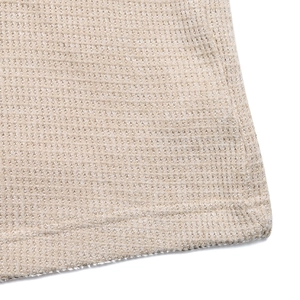 Detailed macro view of beige waffle knit fabric texture and clean hem stitching