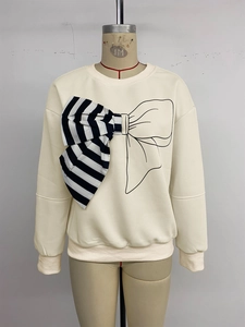 Detail of white crewneck sweatshirt featuring a unique mixed-media bow applique design