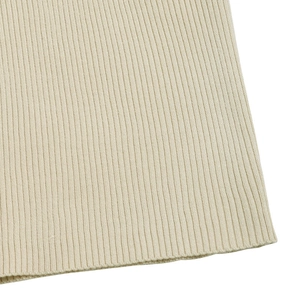Close-up of beige ribbed knit fabric texture on a long sleeve V-neck winter dress