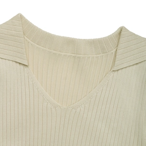 Detail of light beige ribbed knit dress featuring a polo collar and sleek V-neckline