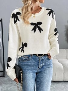 Detail of cream knit sweater with black bow jacquard pattern and ribbed round neck
