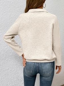Detailansicht eines cremefarbenen Sweatshirts mit strukturierter geometrischer Textur