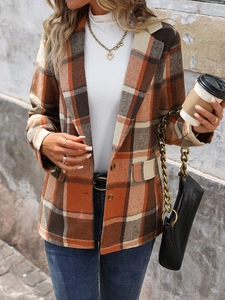 Detail view of plaid blazer texture with black crocodile handbag and gold chain strap