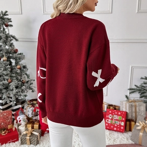 Burgundy Christmas knit sweater with XO pattern sleeves shown in a festive holiday setting