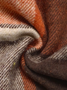 Close-up of the warm plaid fabric showing soft brushed texture and orange wool fibers