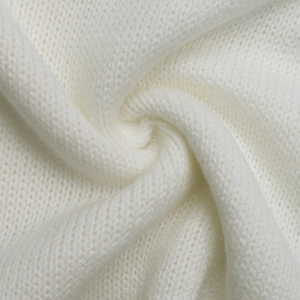 Macro shot of white knitted fabric showing detailed soft flat-stitch texture on sweater