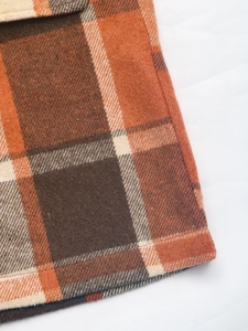 Detailed macro view of heavy brushed plaid fabric with premium stitching on jacket