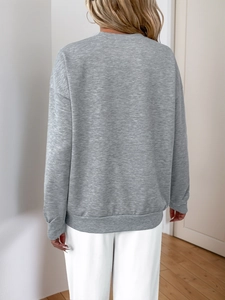 Back view of a loose heather grey long sleeve sweatshirt with ribbed cuffs and hem