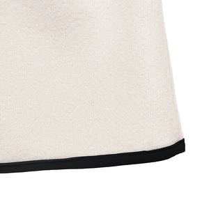 Detailed close-up of white wool coat fabric with black webbing trim and fiber texture