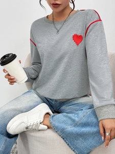 Close-up of gray sweatshirt showing red heart embroidery and red contrast shoulder stripes
